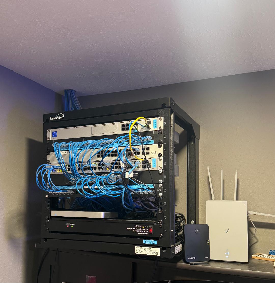 After: clean wall-mounted NavePoint rack with Cisco switches, patch panel, and cable management